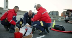 Emergency medical technicians (EMTs) attending to an injured person on the road. The image highlights concerns about potential EMT negligence in providing timely and adequate medical care.